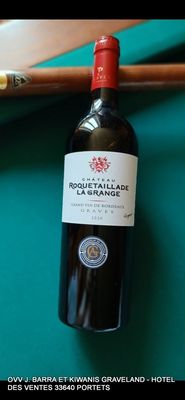 une bouteille de vin posée sur une table de billard, à côté d'une queue de billard