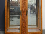 une armoire en bois avec une porte vitrée et une horloge posée dessus