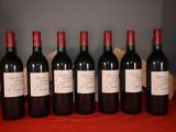 six bottles of red wine are lined up on a table