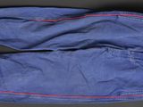 two pairs of blue jeans with red stitching on them on a black surface