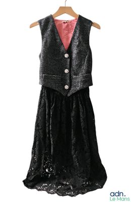 une robe noire avec une chemise rose et un gilet, suspendue à un cintre