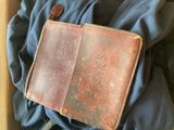 un vieux portefeuille en cuir marron posé sur un tissu bleu