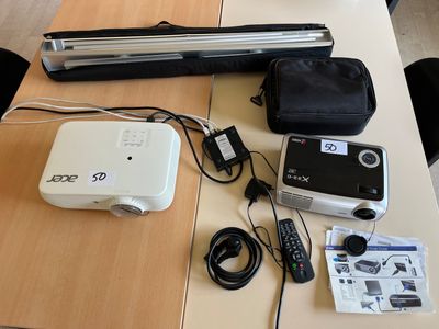 une table sur laquelle se trouvent un projecteur, une télécommande et d'autres appareils électroniques