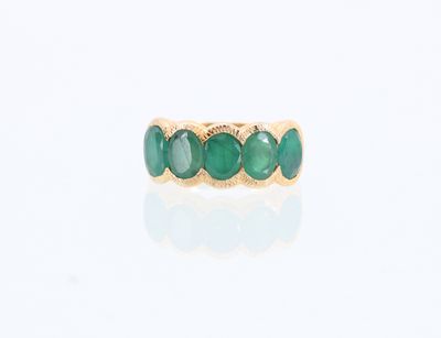un gros plan d'une bague en or sertie de pierres vertes