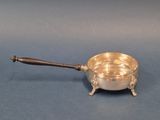 une assiette ancienne en argent avec un manche en bois sur fond bleu