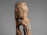 a wooden statue of a person with a head on a rock