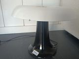 une table noire sur laquelle est posée une lampe blanche