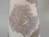 a white vase with purple flowers on it sitting on a table