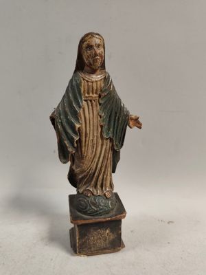 statue d'une femme tenant une croix, posée sur un socle en bois
