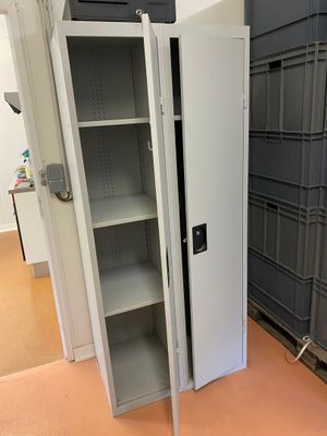 une grande armoire métallique dont la porte est ouverte, dans une pièce