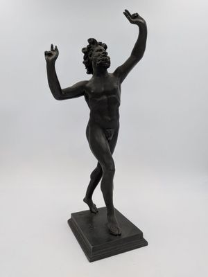 une statue noire représentant une femme tenant une fleur à la main