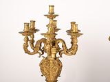 two gold colored candeliers with candles on them