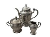 a silver tea pot and two cups on a white background