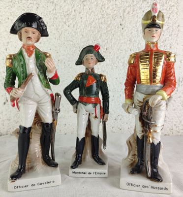three figurines of men dressed in military uniforms