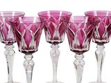 purple glass goblets are lined up in a row on a white surface