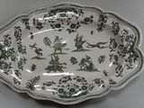 a green and white plate with birds and flowers on it