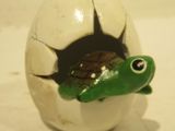 a small toy turtle sitting inside of an egg shell