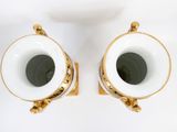 two white and gold vases sitting on a white surface