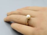 Une bague en perle plaquée or à la main d'une femme