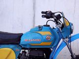 a blue and yellow motorcycle parked next to a white wall