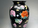 a black vase with colorful flowers on it on a white surface