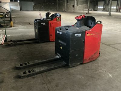two forklifts that are sitting in a warehouse