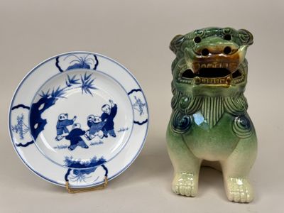 une assiette posée sur une autre assiette, à côté d'un chien en céramique
