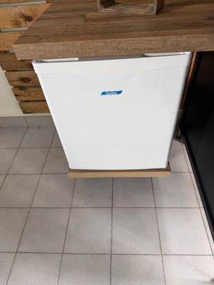 un petit réfrigérateur blanc posé dans une cuisine, à côté d'un plan de travail