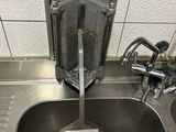 un lavabo en acier inoxydable dans des toilettes publiques, sur lequel est apposée une pancarte