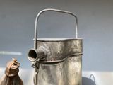 a small metal bucket with a handle next to a small bag