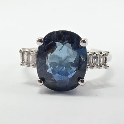 gros plan d'une bague avec un saphir bleu entouré de diamants blancs