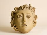 une statue représentant le visage d'un homme sur une surface blanche