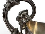 an antique silver plated bowl with a handle and a flower decoration