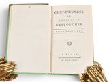 an open book with a gold glove on top of it