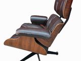 un fauteuil de salon en cuir marron, avec un piètement en bois et une assise rembourrée de cuir noir