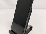 the back of a black cell phone on a stand on a white surface