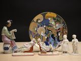 plusieurs figurines représentant des femmes asiatiques et une assiette posées sur une table