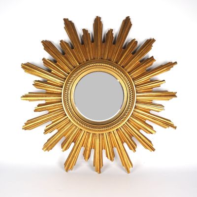 un miroir en forme d'étoile dorée accroché à un mur blanc
