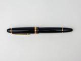 a black and gold fountain pen sitting on top of a white surface
