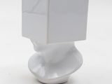 a small white sculpture with a book on top of it