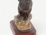 statue of a bear sitting on a rock on a wooden base