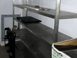 un homme debout dans une cuisine, à côté d'une étagère en métal