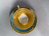 gold and blue cup and saucer on a white surface