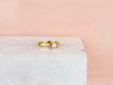 une bague de fiançailles en or sertie d'un diamant, posée sur un bloc de marbre blanc