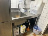 a sink in a small kitchen with a bucket and a mop