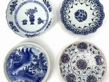 four blue and white plates with designs on them on a white surface