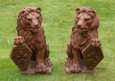 deux statues de lions assis dans l'herbe