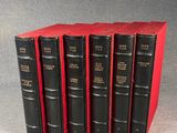 six black books are lined up in a row on a gray surface