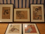 three framed asian paintings on a wooden table with a blue and white striped wall