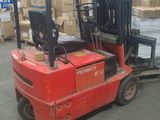un chariot élévateur rouge chargé de cartons dans un entrepôt